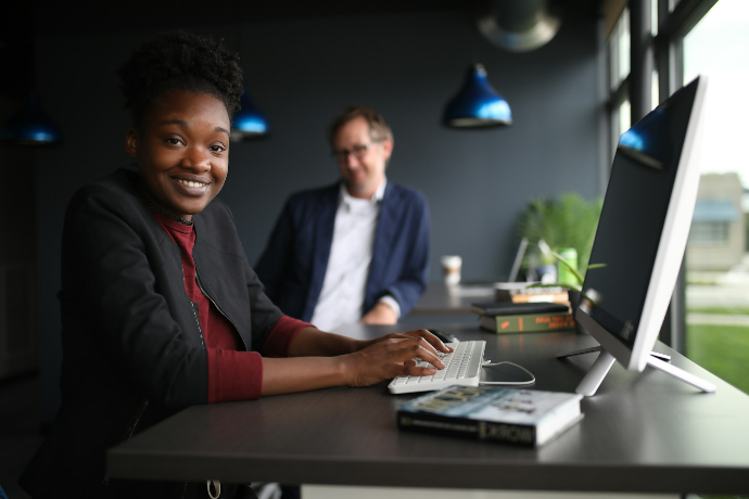 a man and a woman sitting at a desk in front of a computer
